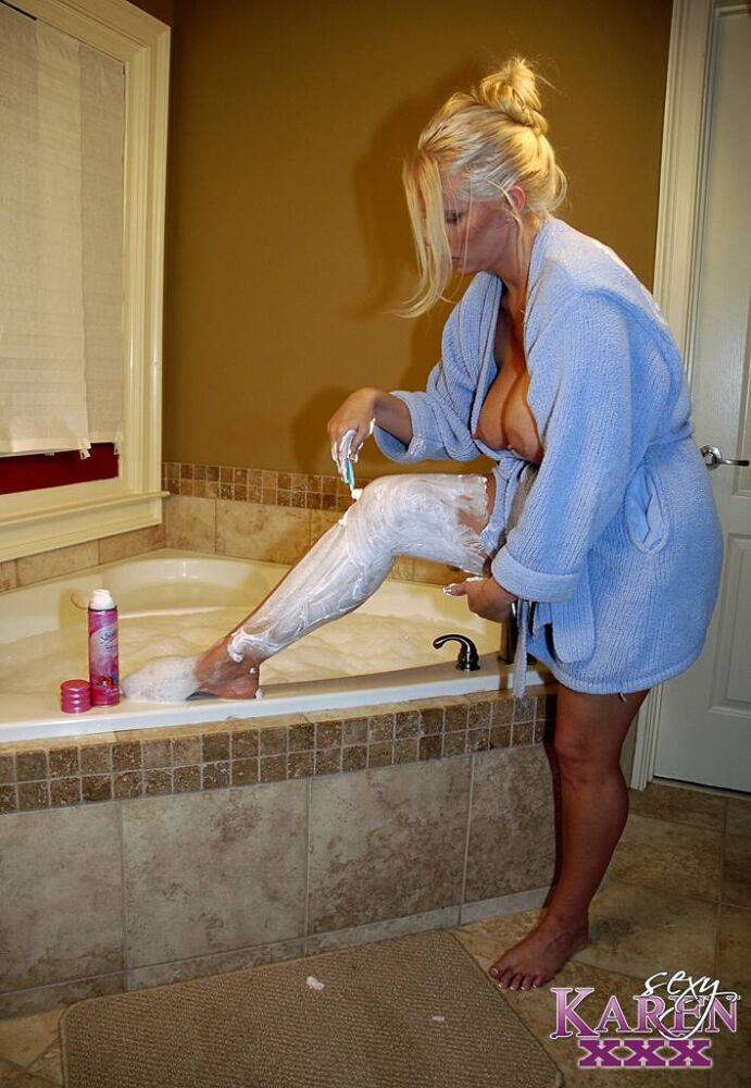 Busty blonde lady Karen Fisher shaved her legs and vagina on the side of a tub | Photo: 907840