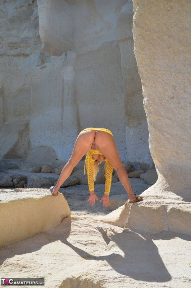 Mature woman Sweet Susi stands naked on rocks with her legs spread apart - #11