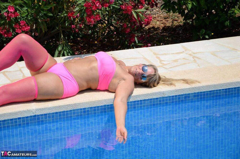 Older blonde amateur Sweet Susi shows her tits and ass beside a pool in shades - #11