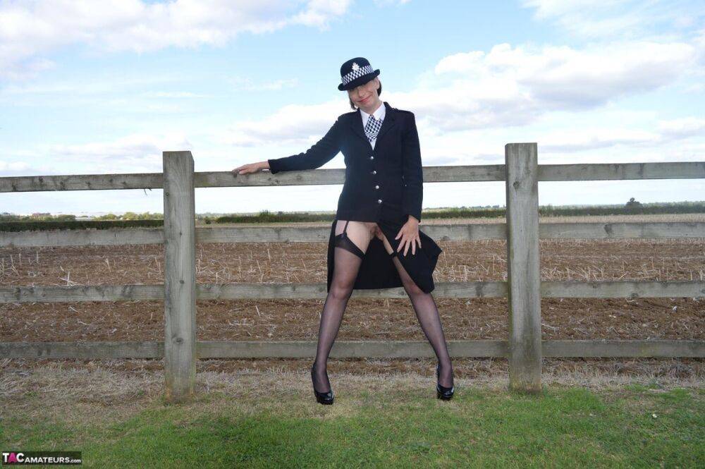 Mature policewoman Barby Slut removes her uniform against a fence at a farm - #11