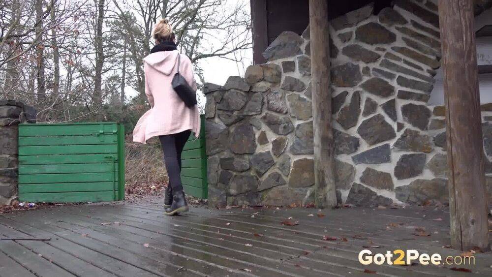 White girl Cynthia Vellons takes a piss on a deck behind a stone structure - #6