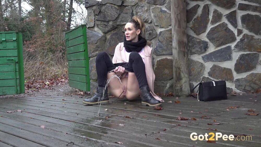 White girl Cynthia Vellons takes a piss on a deck behind a stone structure - #15