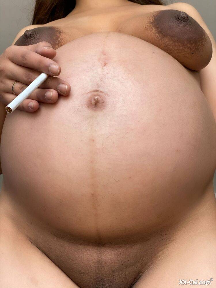 Pregnant smoker Leila teasing nude with her bulging tummy & her dark nipples | Photo: 4003113
