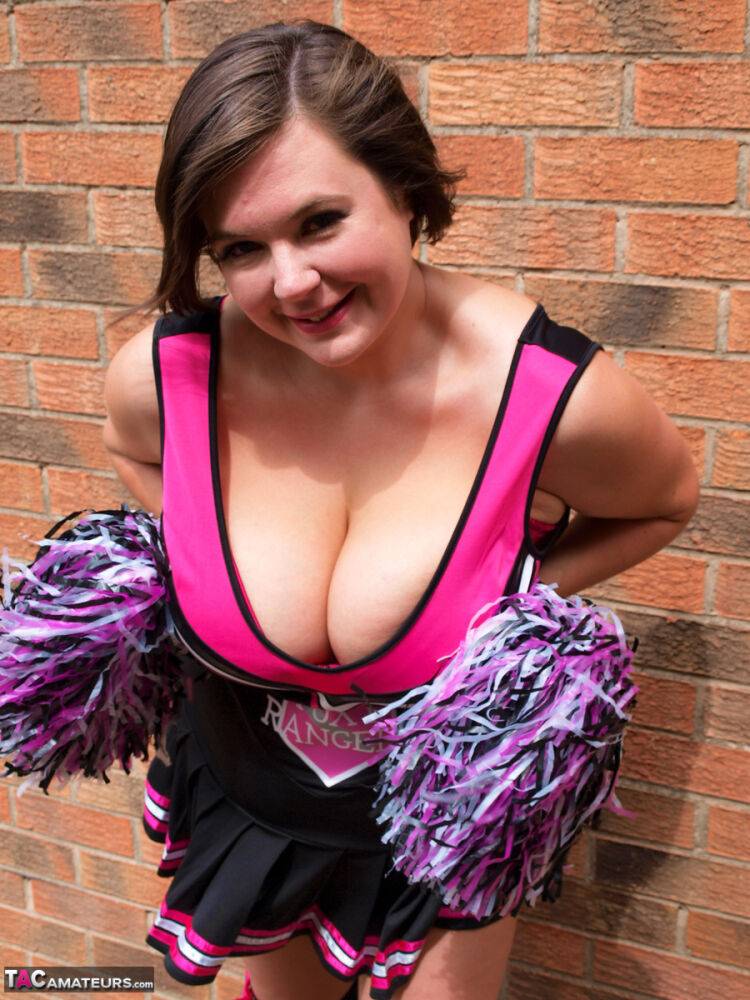 Chubby cheerleader Roxy uncovers her large tits against a brick wall - #13