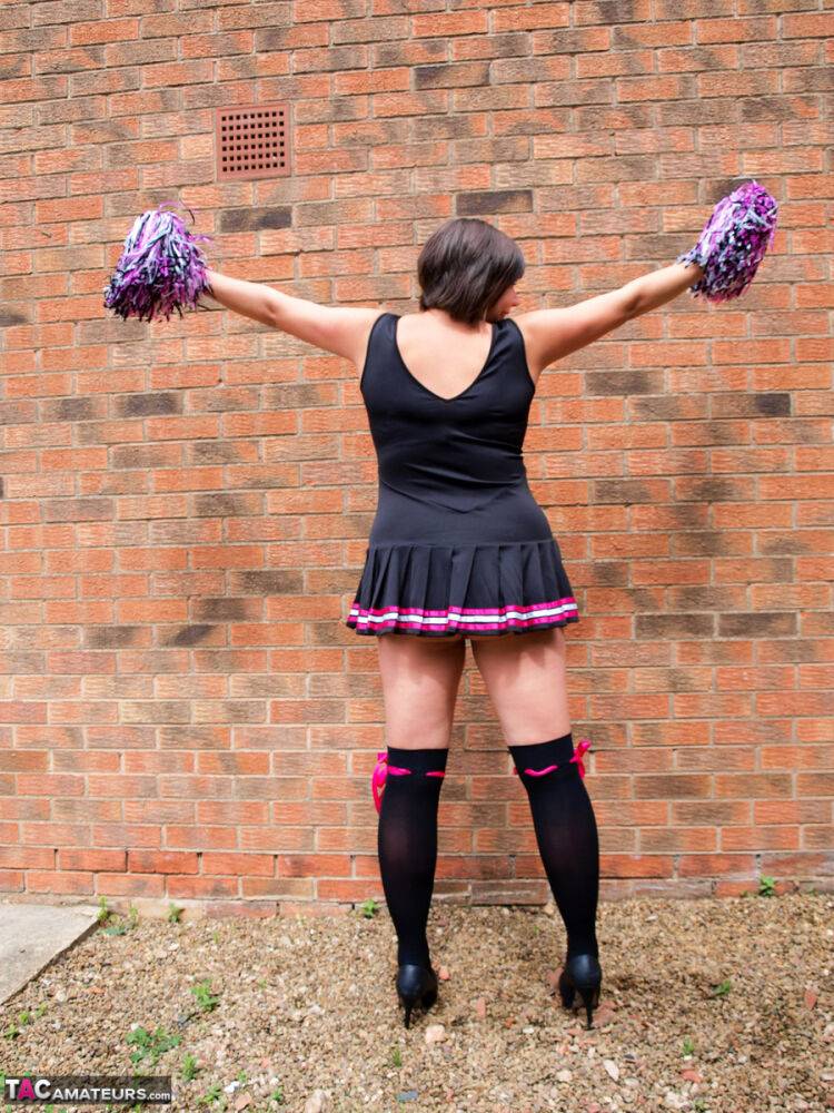 Chubby cheerleader Roxy uncovers her large tits against a brick wall - #16