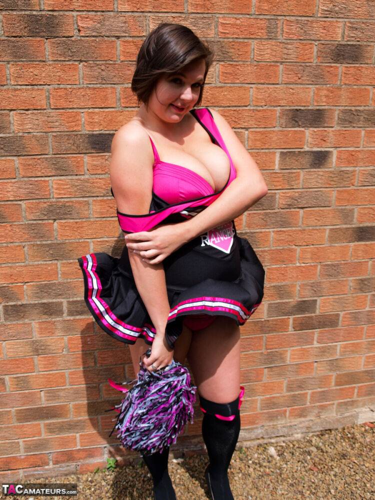 Chubby cheerleader Roxy uncovers her large tits against a brick wall - #1