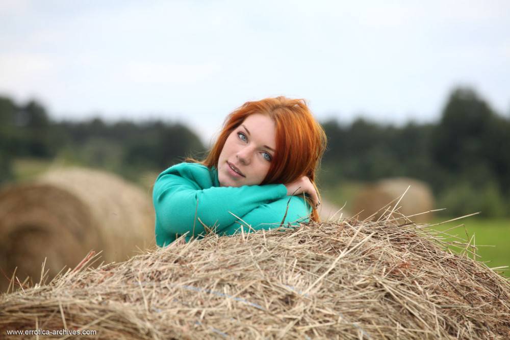 Redhead amber a poses on the stack of hay baring her smooth pussy - #1