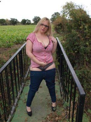 Amateur BBW Sindy Bust exposes her big boobs and twat on a countryside bridge on nudepicso.com