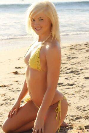 Blonde glamour model Ashlie Madison poses alone on a beach in a yellow bikini on nudepicso.com