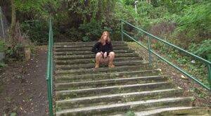 Natural redhead Chrissy Fox squats for a pee on a set of public steps on nudepicso.com