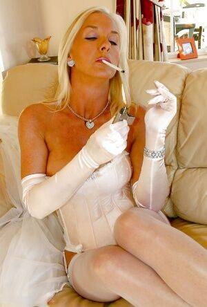 Glamorous mature vixen in snazzy lingerie and nylons smoking a cigarette on nudepicso.com