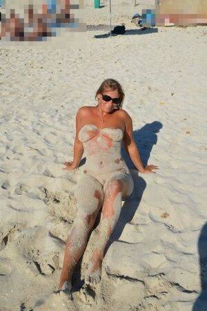 Naked amateur Sweet Susi covers her body in beach sand in sunglasses on nudepicso.com