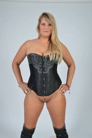 Mature blonde Sweet Susi displays her trimmed pussy in a corset and OTK boots on nudepicso.com