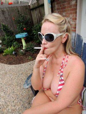 Fat blonde Dee Siren smokes while taking off a bikini in the backyard on nudepicso.com