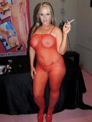 Amateur BBW Dee Siren smokes before facial cumshots in a red bodystocking on nudepicso.com