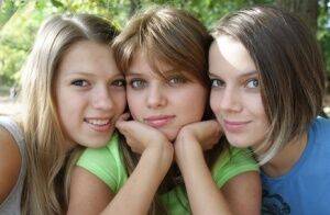 Three young looking girls gets naked on a wooden bench in the countryside on nudepicso.com