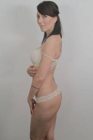 Tattooed milf Zoe Holloway showing off in a white lingerie and panties on nudepicso.com