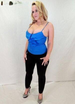 Middle-aged blonde Dee Siren displays her ample cleavage in black leggings on nudepicso.com