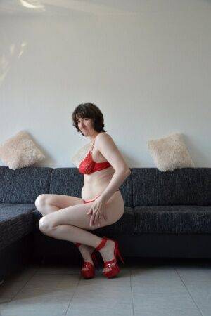 Solo model Hot MILF kicks off red panties with matching heels on a sofa on nudepicso.com