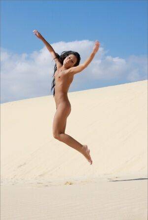 Totally naked brunette models by herself on a sand dune on nudepicso.com