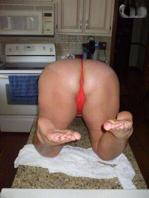 Older amateur Busty Bliss gets naked on a kitchen counter in a thong on nudepicso.com