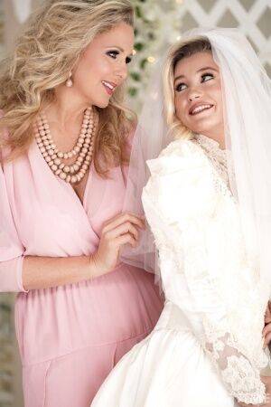 Carolina Sweets is affixed with a garter before a lesbian wedding to Julia Ann on nudepicso.com