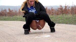 Fully clothed girl Naomi Bennet pulls down her pants to piss on a dirt road on nudepicso.com