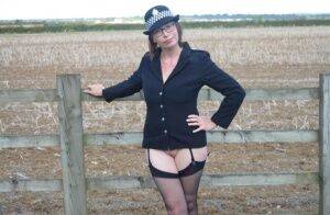 Mature policewoman Barby Slut removes her uniform against a fence at a farm on nudepicso.com