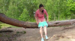 Brunette female Antonia Sainz squats by a fallen tree to take a piss on nudepicso.com