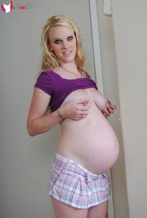 Blonde girl Hydii May puts her pregnant belly on display in knee socks on nudepicso.com