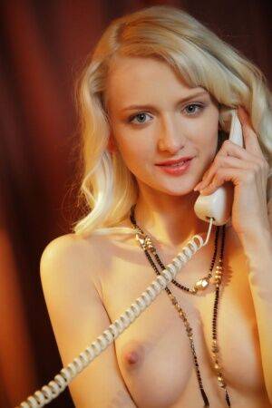 Sweet blonde teen Nika N answers the telephone while wearing a garter belt on nudepicso.com