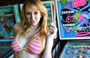Brett Rossi fingers her pussy in striped OTK socks atop pinball machine on nudepicso.com