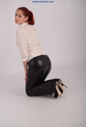 Sexy redhead in leather pants and heels unbuttons her white blouse on nudepicso.com