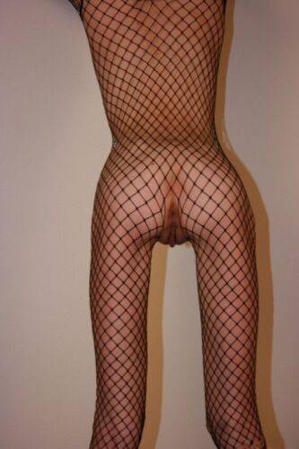 Solo model with a shaved head poses in a fishnet bodystocking on nudepicso.com