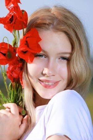 Sweet teen Genevieve Gandi strips naked in a field of blooming flowers on nudepicso.com