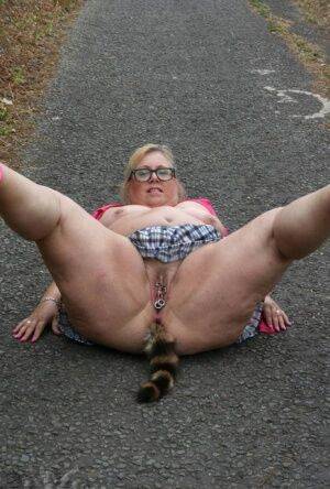 Fat UKwoman Lexie Cummings walks a path sporting a raccoon tail butt plug on nudepicso.com