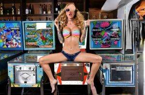 Inked chick Sarah Jessie toys her pussy atop a pinball machine while alone on nudepicso.com