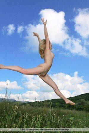 Flexible blonde teen Thea C juggles while completely naked in a field on nudepicso.com