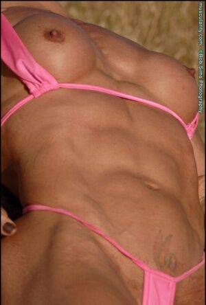 Middle-aged bodybuilder Emery Miller releases her boobs from a pink bikini on nudepicso.com